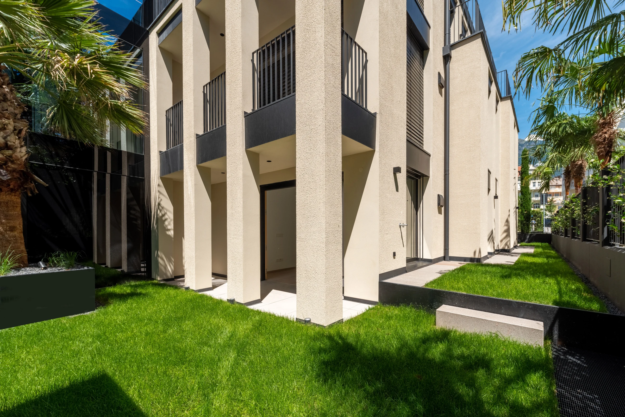 Privater Garten der Wohnung W3 mit Palmen und der charakteristischen Architektur des Hartmann Haus II